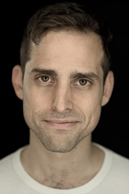 Close portrait of Aaron against black, a slight smile