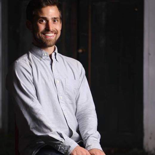 Aaron seated in a blue shirt, smiling